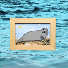 Load image into Gallery viewer, Framed glass artwork of a seal on a beach with ocean waves in the background
